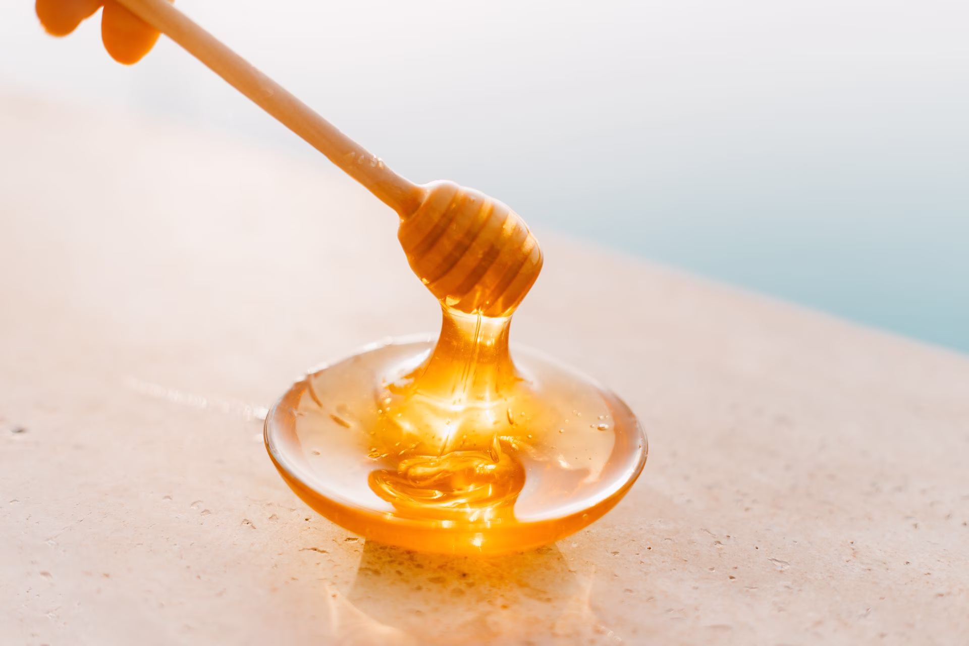Glass jar of golden honey with wooden dipper